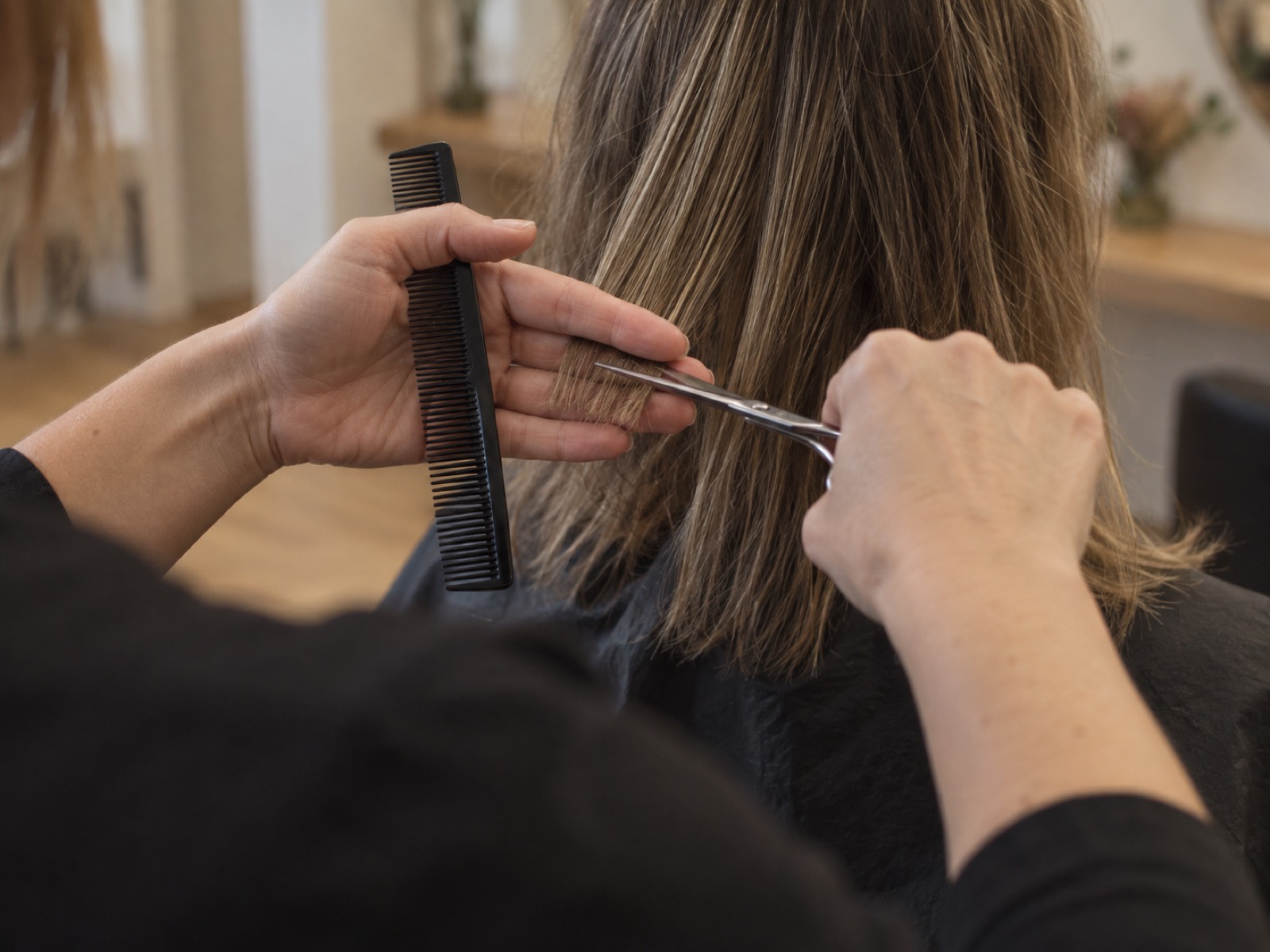Hände mit Schere und Kamm beim Haarschnitt