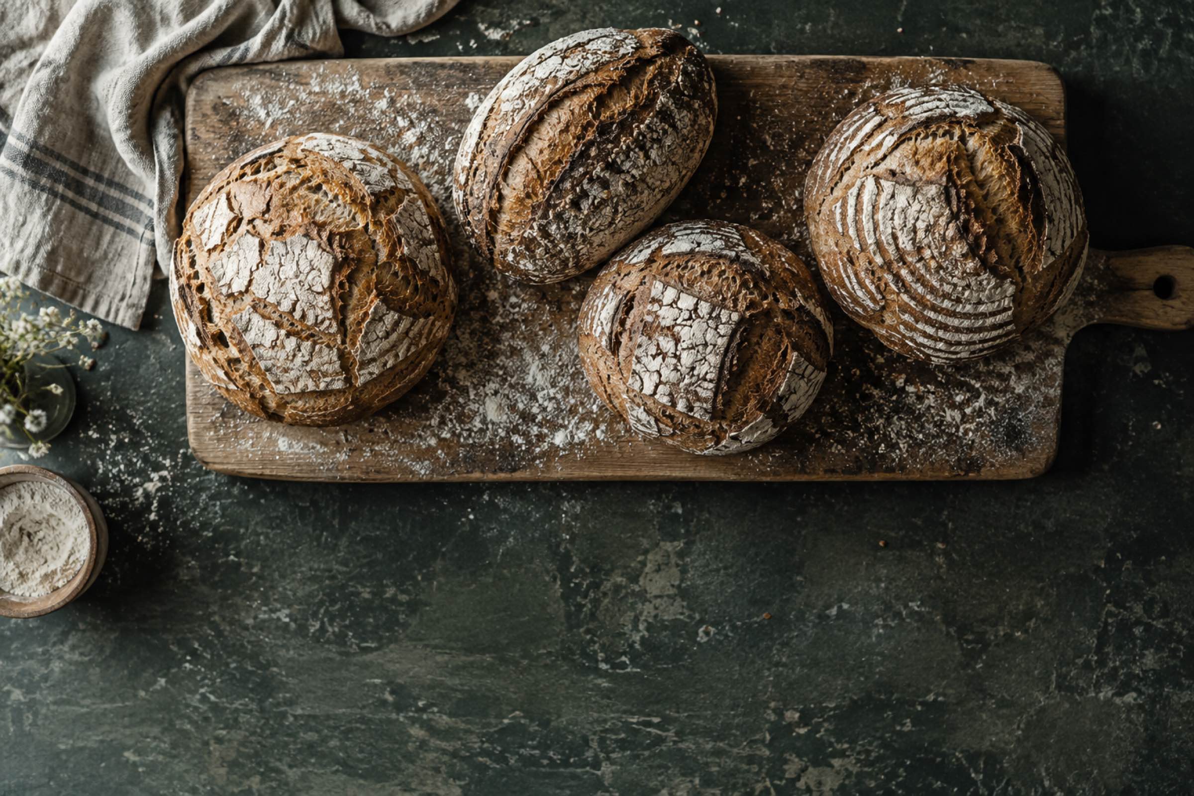 Vier Brotlaibe auf einem bemehlten Holzbrett